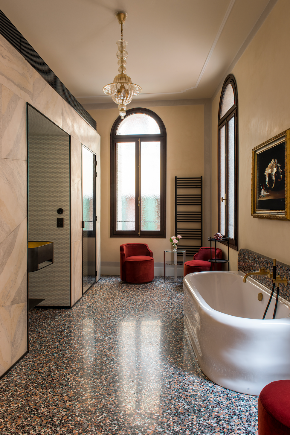 Luxurious bathroom with a freestanding bathtub, red chairs, and large windows at Nolinski Hotel Venice